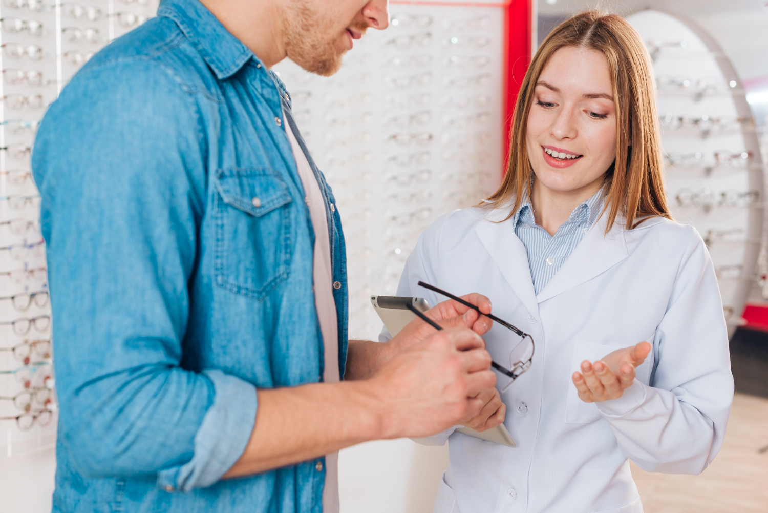 Optometrist assisting male customer selecting eyeglasses in optical shop