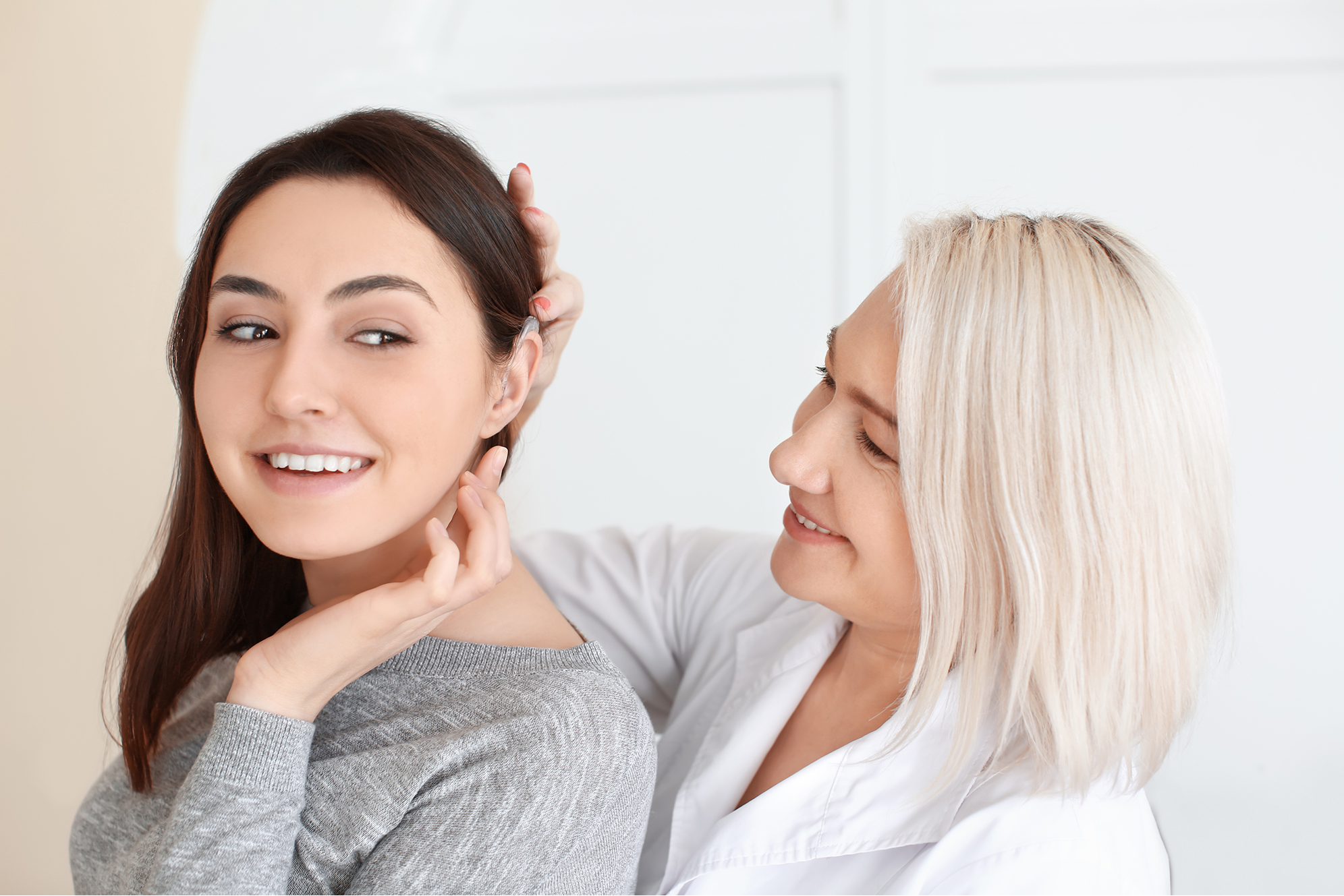 Two smiling women of different ages touching each other's faces affectionately indoors.