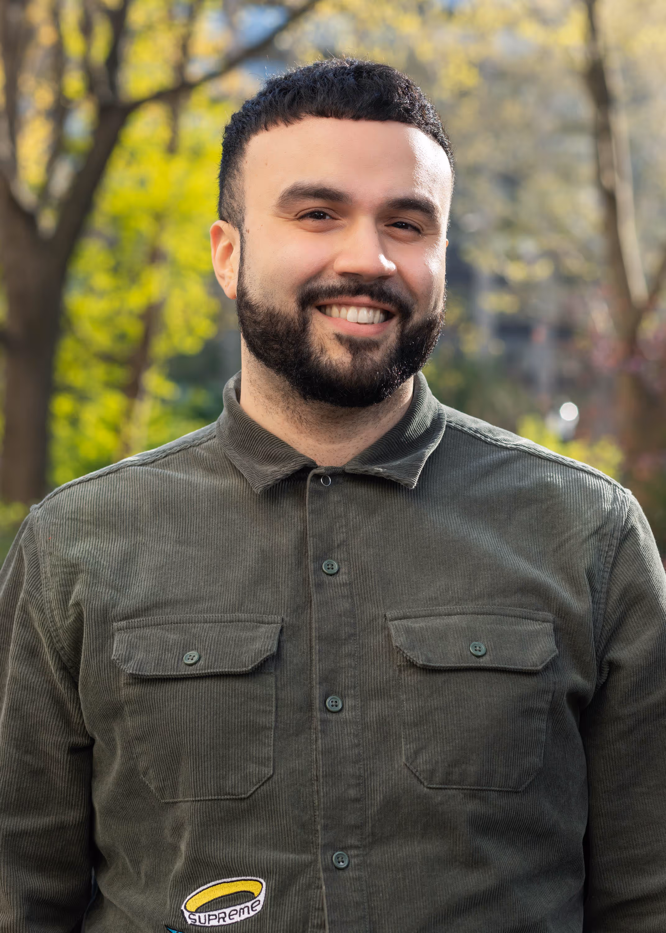 Smiling IT professional in olive shirt standing outdoors, representing Point MSP's New York City managed services team