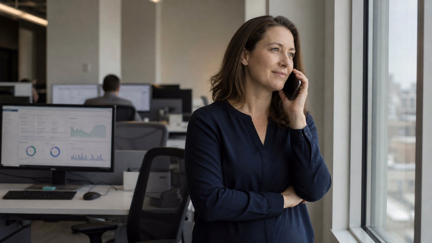 Woman with phone by window, muted light, business call 63 chars
