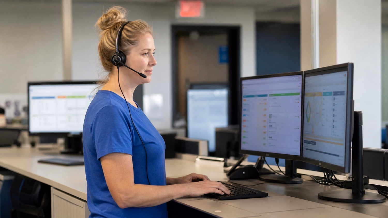 Help desk agent at counter with headset and monitors