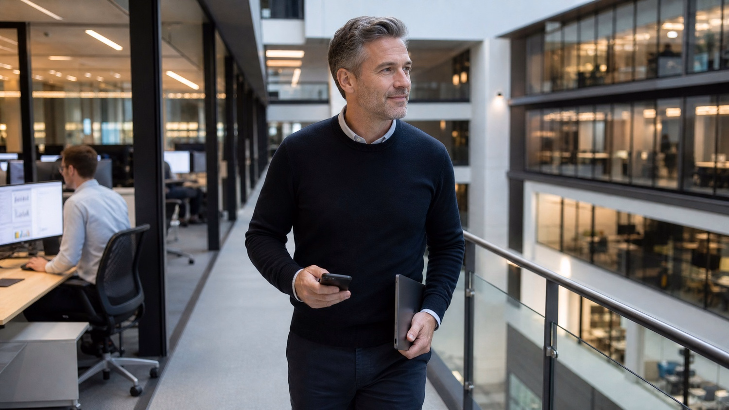 Man walks atrium, iPhone and tablet in hand 54 chars