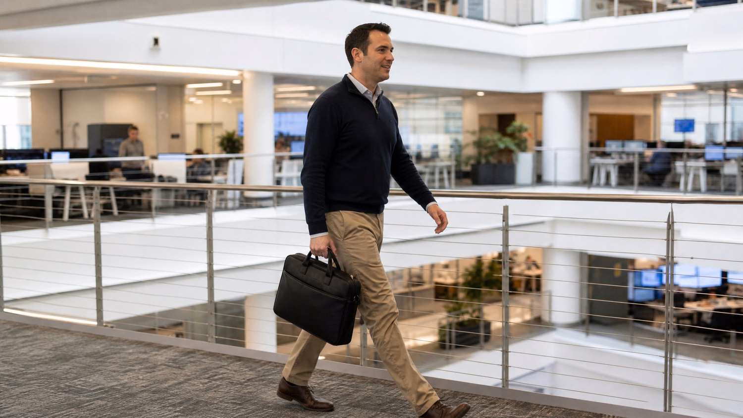 Man walking briskly across modern office atrium walkway