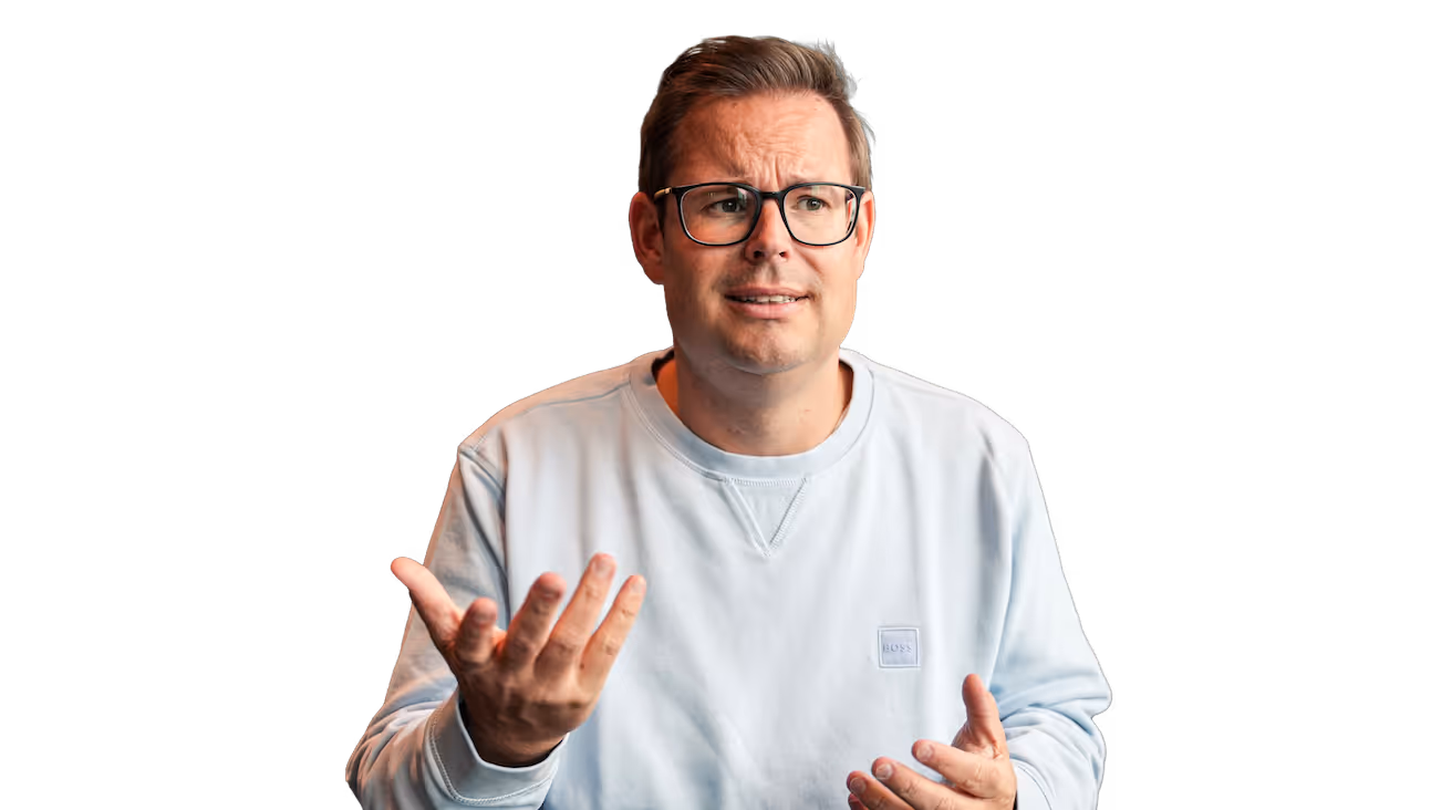 Mann mit Brille in hellblauem Pullover gestikuliert und sieht nachdenklich aus.