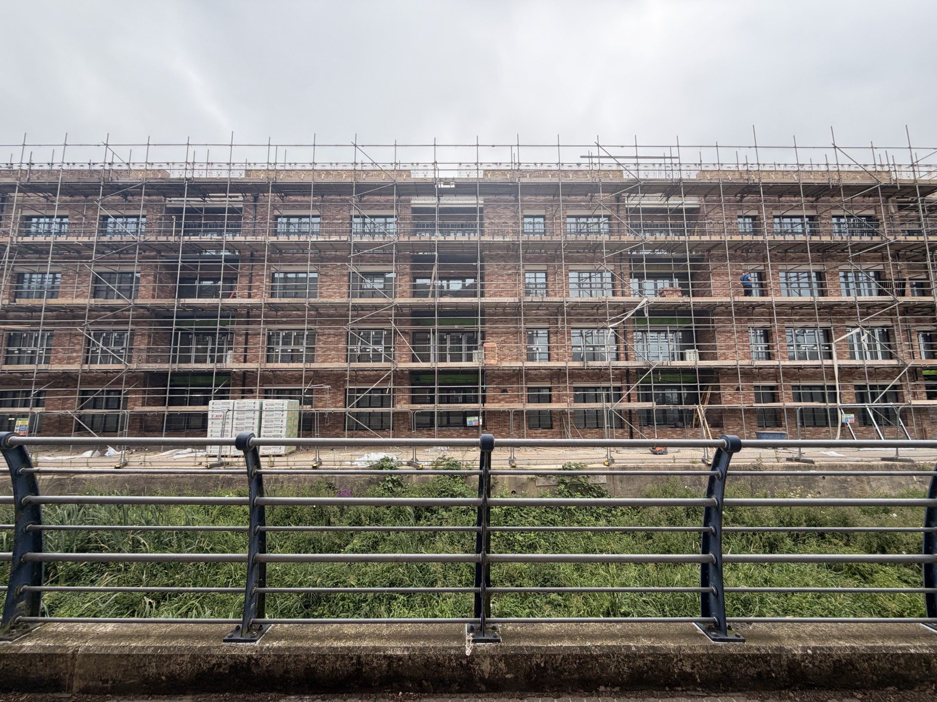 Apartment buildings by a calm river at sunset with colorful clouds and lights reflecting in the water.
