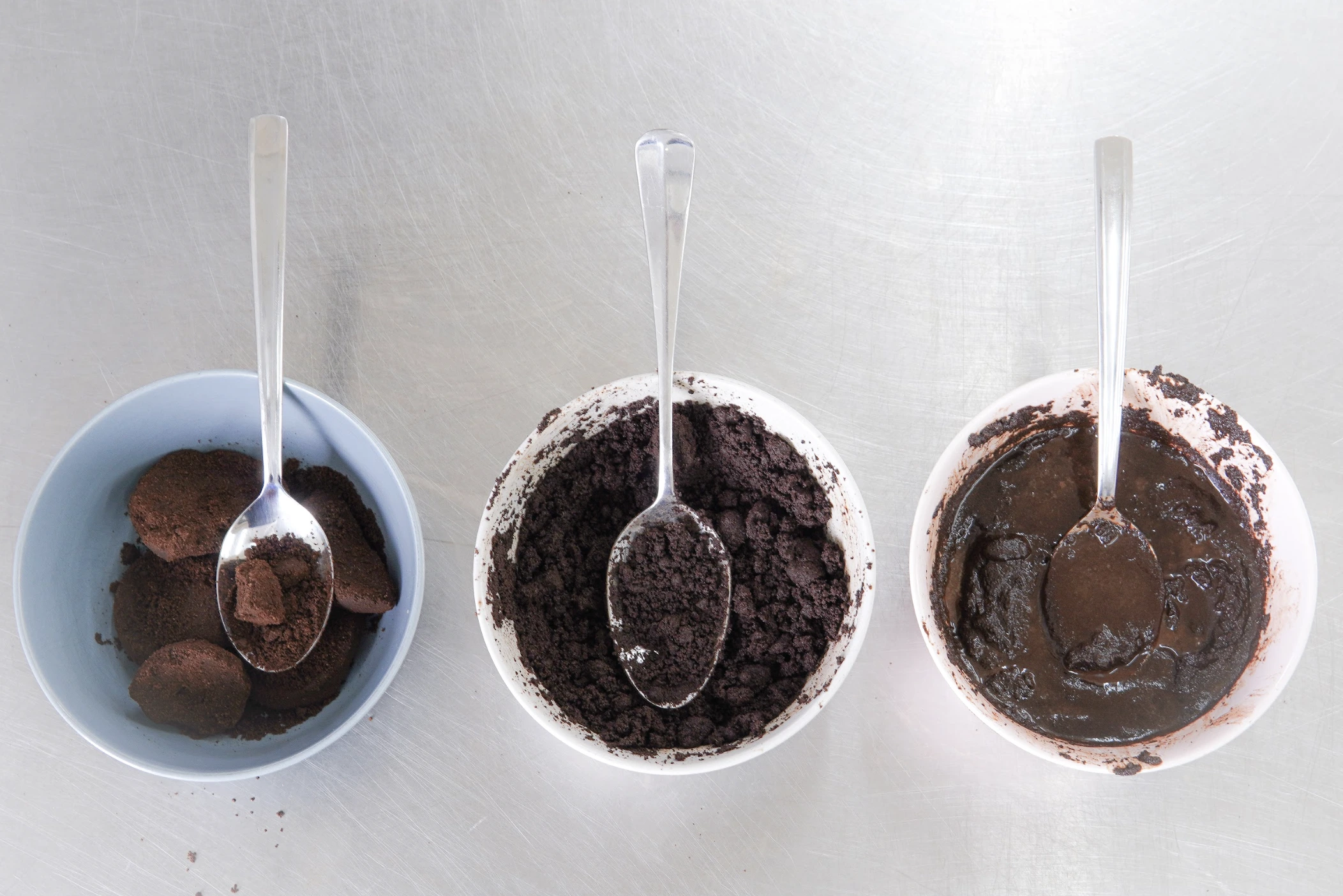 Three bowls showing coffee grounds with increasing moisture from dry clumps to wet paste.
