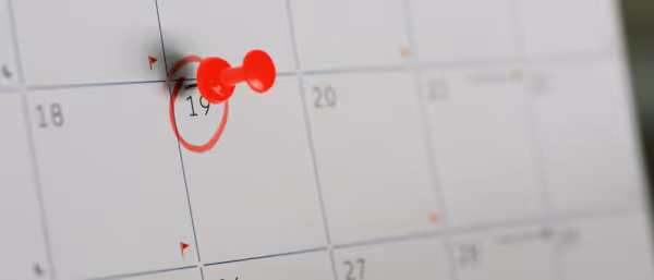 Red pushpin marking the 19th day on a wall calendar.