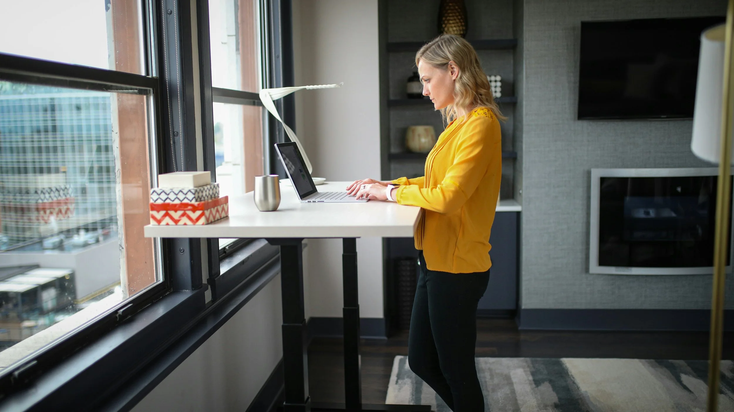 woman in yellow cardigan working at a standing desk