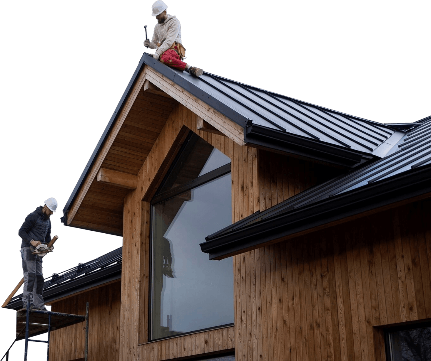 Two construction workers wearing white helmets working on a modern wooden house roof with black metal panels, one on scaffolding holding a circular saw and the other sitting on the roof using a hammer.