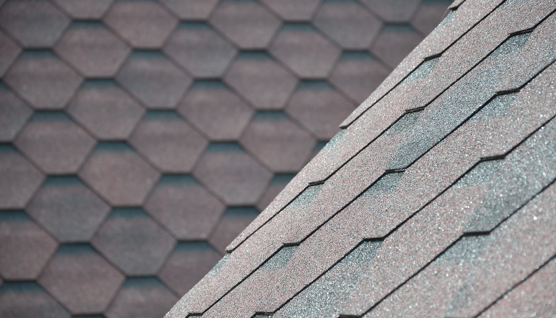Close-up of gray hexagonal asphalt roof shingles arranged in overlapping rows.