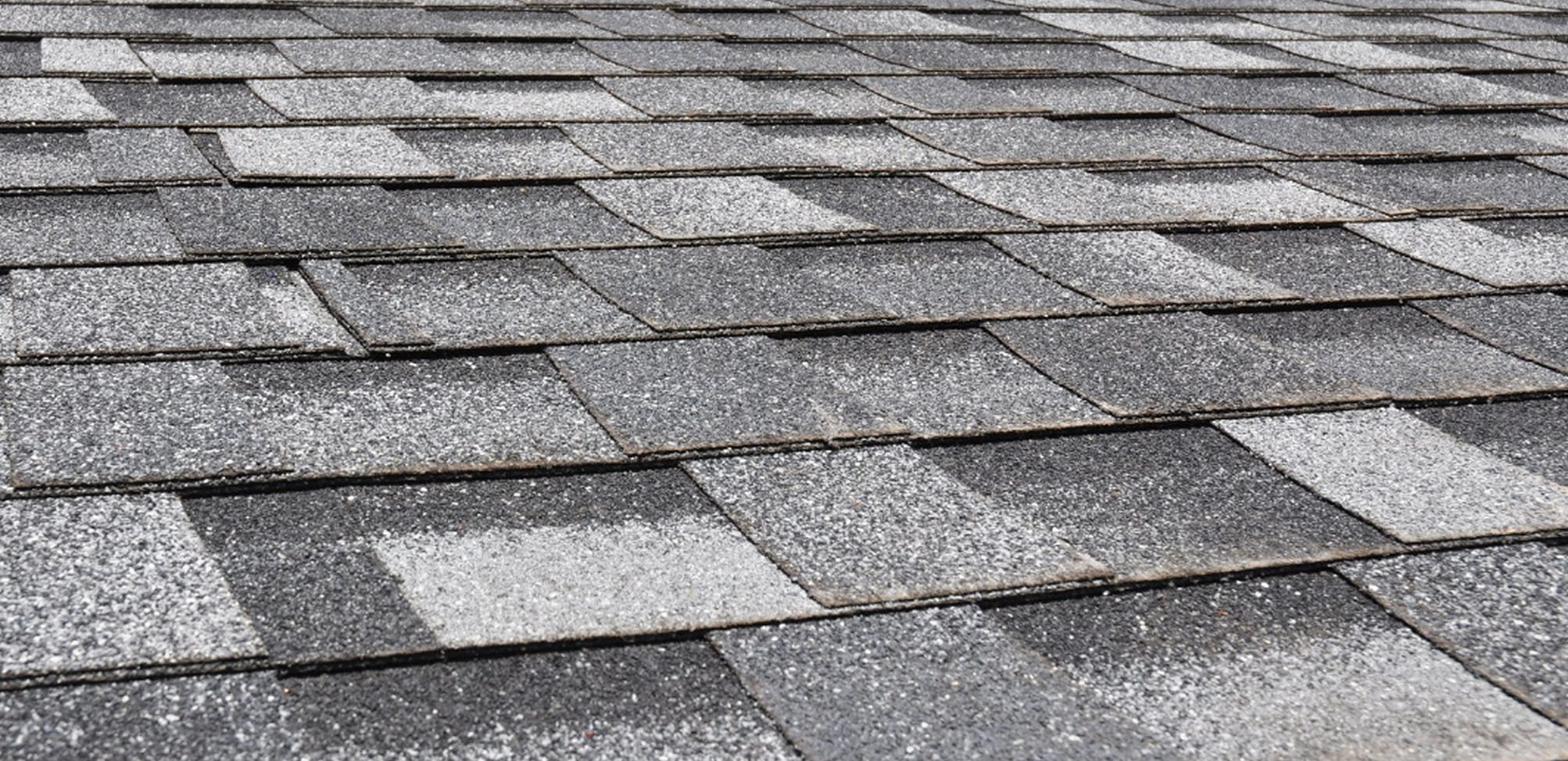 Close-up view of gray asphalt roof shingles arranged in a neat overlapping pattern.