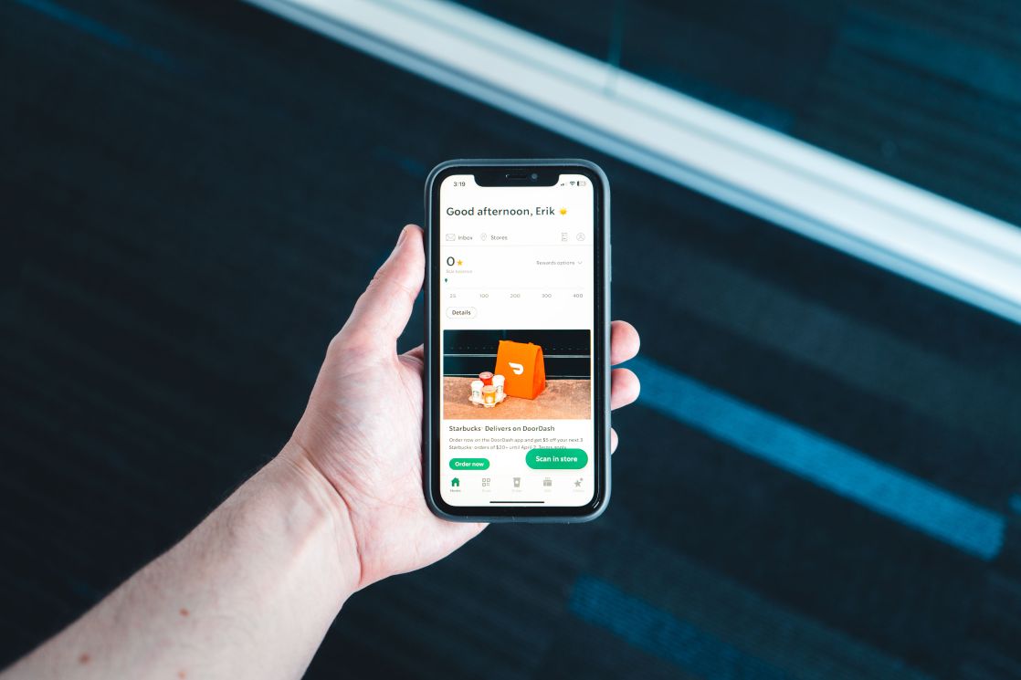 Hand holding smartphone with food delivery app on screen in bright setting
