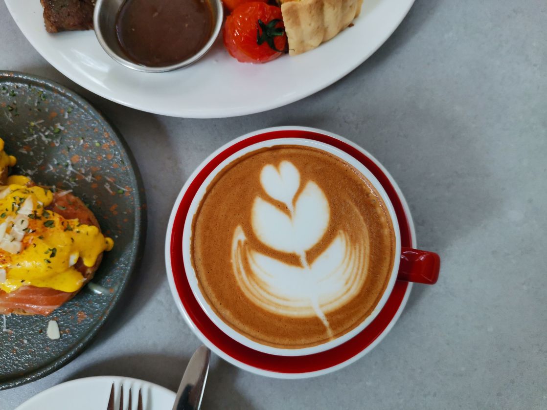 Aerial view of a latte with art, served alongside a delicious breakfast spread.