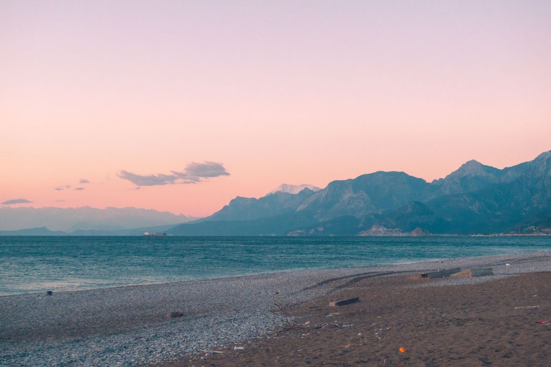 Tranquil coastal landscape with mountains and pink sky at sunset, perfect for nature lovers.