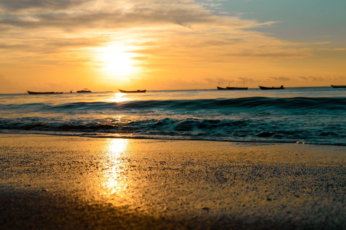 Beautiful sunset over Cumuruxatiba beach with boats on the ocean in Brazil.