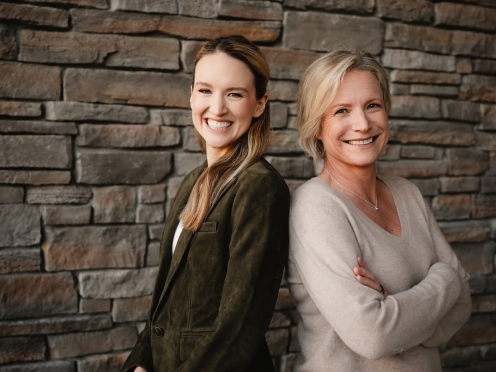 Two professional women posing in front of brick wall at dental practice