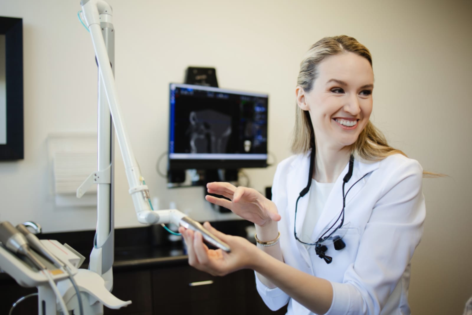 Female dentist in white coat explaining dental treatment using dental models and tools