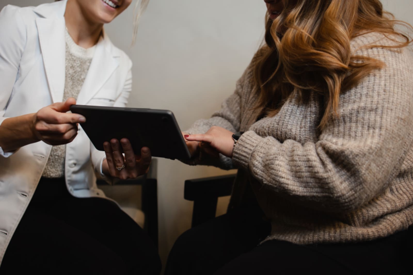 Two people reviewing dental treatment options on a tablet in a clinical consultation setting.