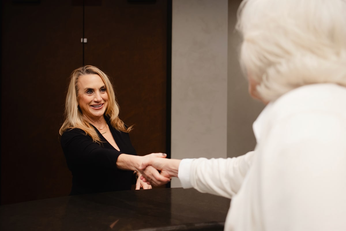 Dentist shaking hands with a patient in a clinical setting