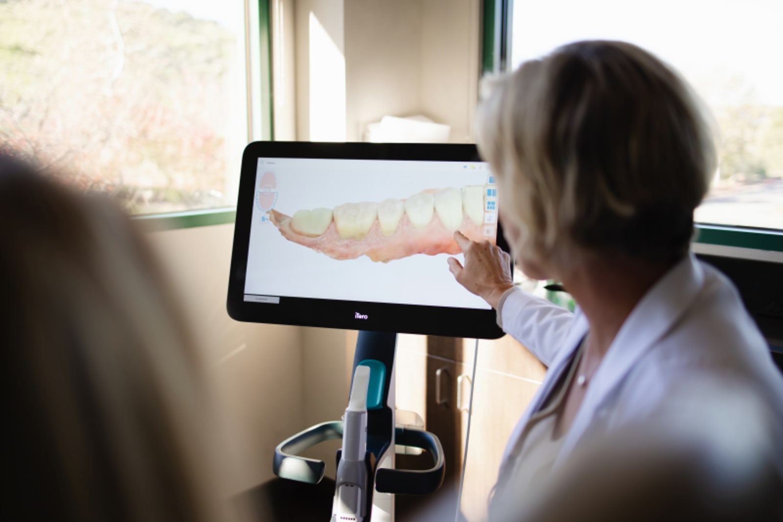 Dentist discussing smile design with patient on digital display