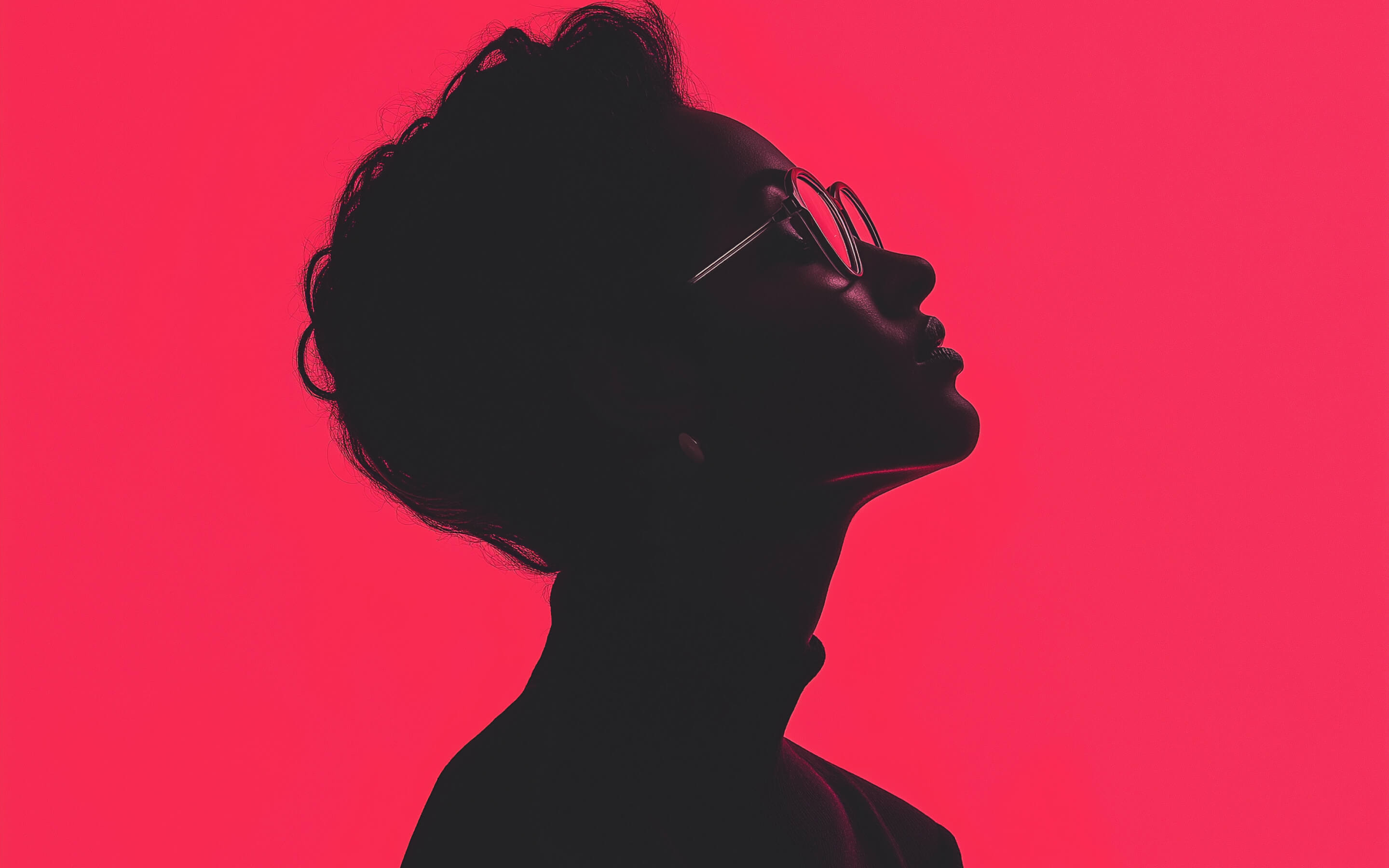 Silhouette of a person wearing glasses against a bright pink background, profile view.