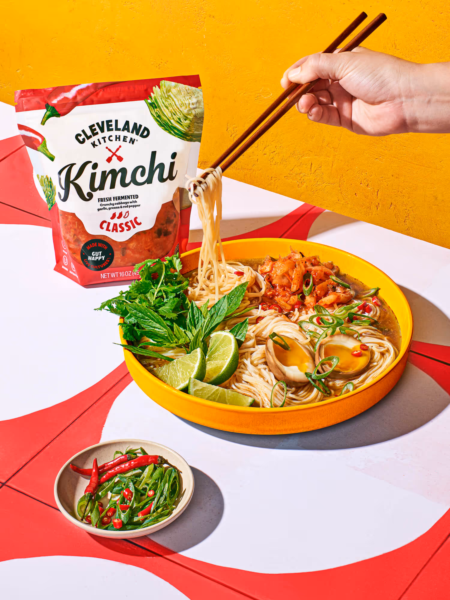 Bowl of ramen topped with Cleveland Kitchen Classic Kimchi, soft-boiled egg, herbs, and lime