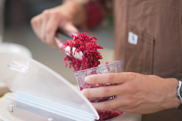 A person holding tongs with sauerkraut in them