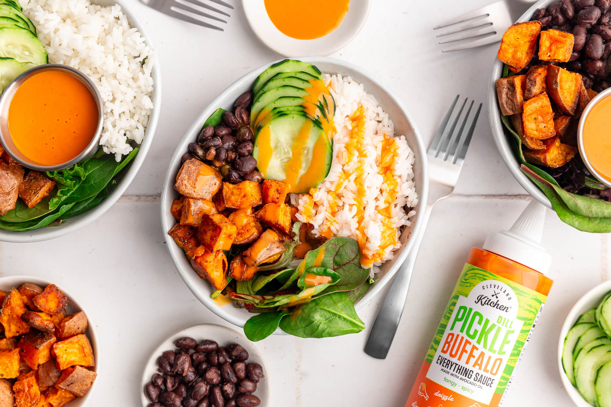 A healthy rice bowl with sweet potato, black beans and greens drizzles with Cleveland Kitchen Dill Pickle Buffalo Everything Sauce.