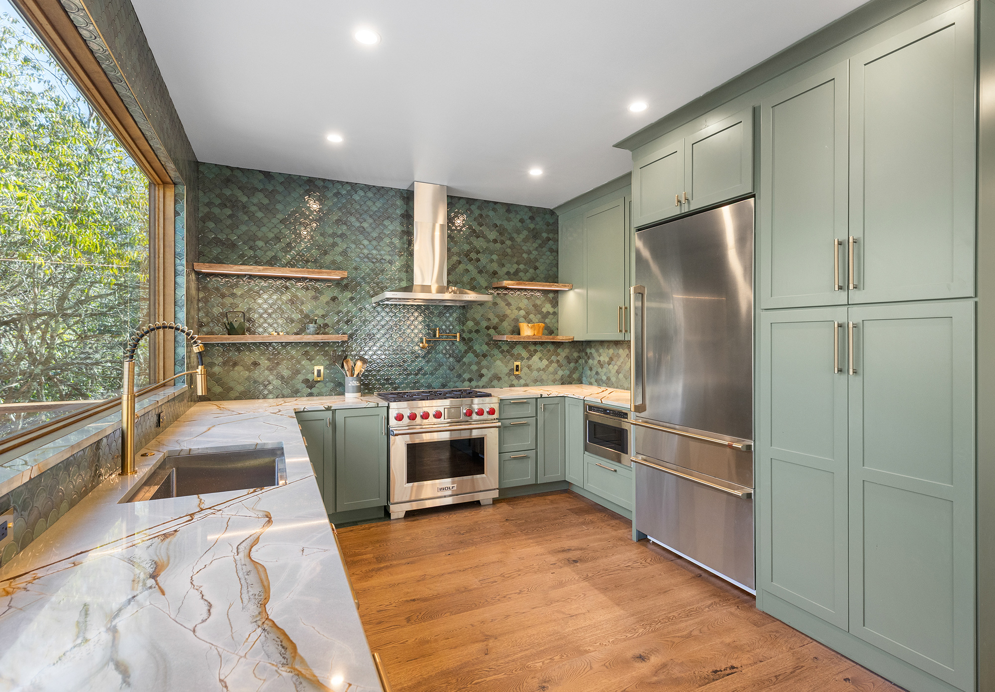 A beautiful custom kitchen with classic muted greens and beautiful granite and hardwoods built by Down River Builders.