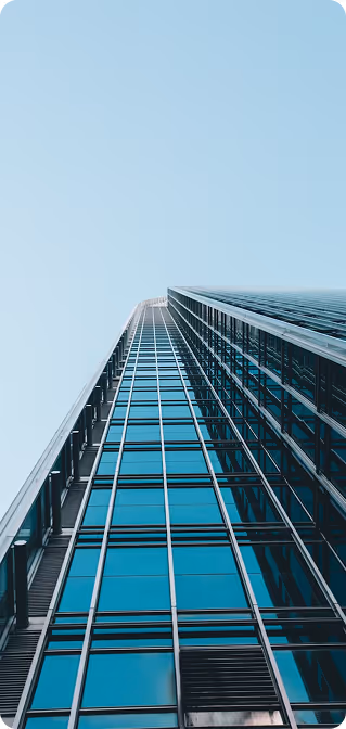 Low-angle view of a tall modern glass skyscraper against a clear blue sky.