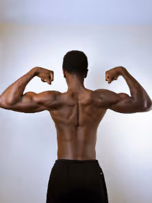 Muscular man showing his back and flexing biceps with both arms raised.
