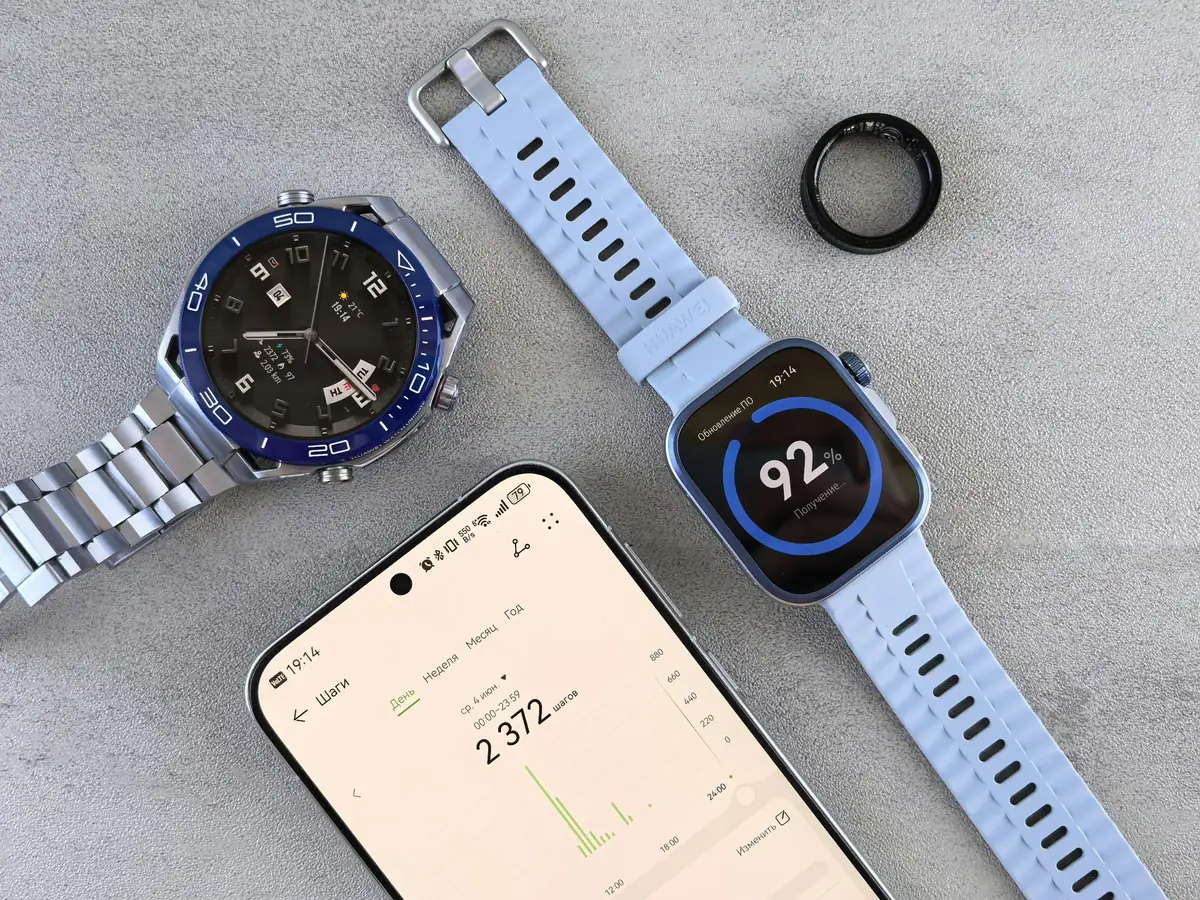 Smartwatch with light blue strap showing 92% progress next to a metal analog watch and a smartphone displaying step count in Russian.