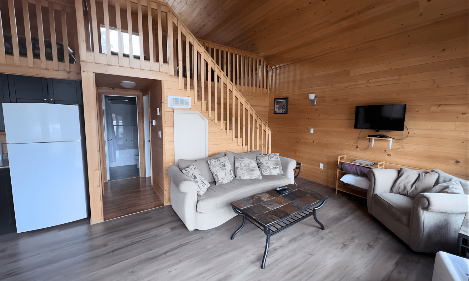 cabin interior with white sofa, brown armchair, and bedroom area