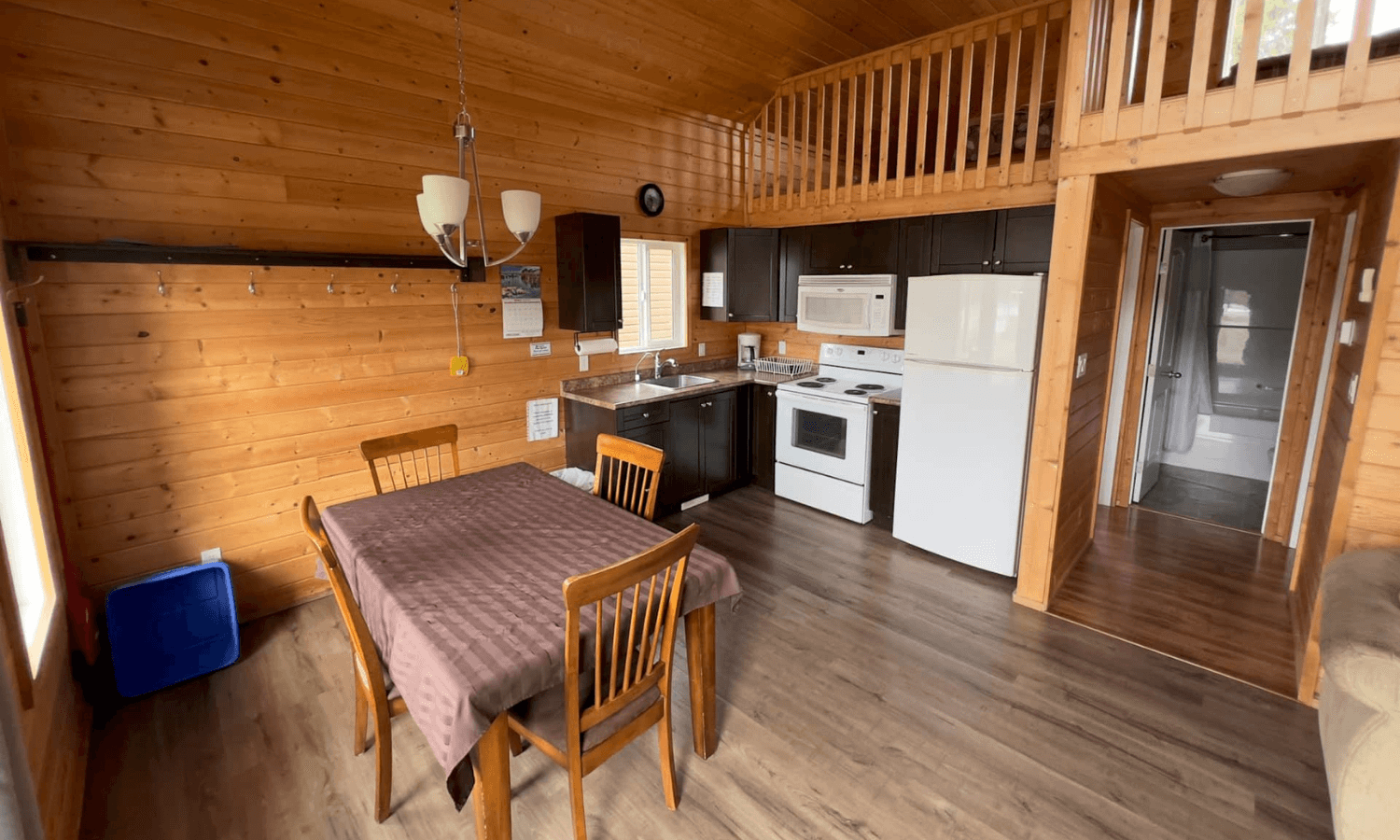 cabin interior with wooden dining table, chairs, and kitchen area