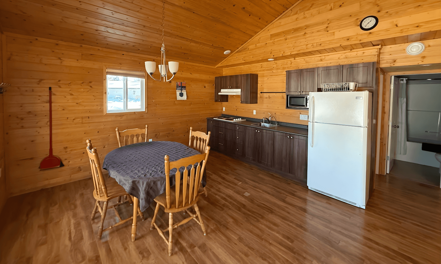 Cozy wood-paneled cabin dining area with a four-seat table, and kitchen.