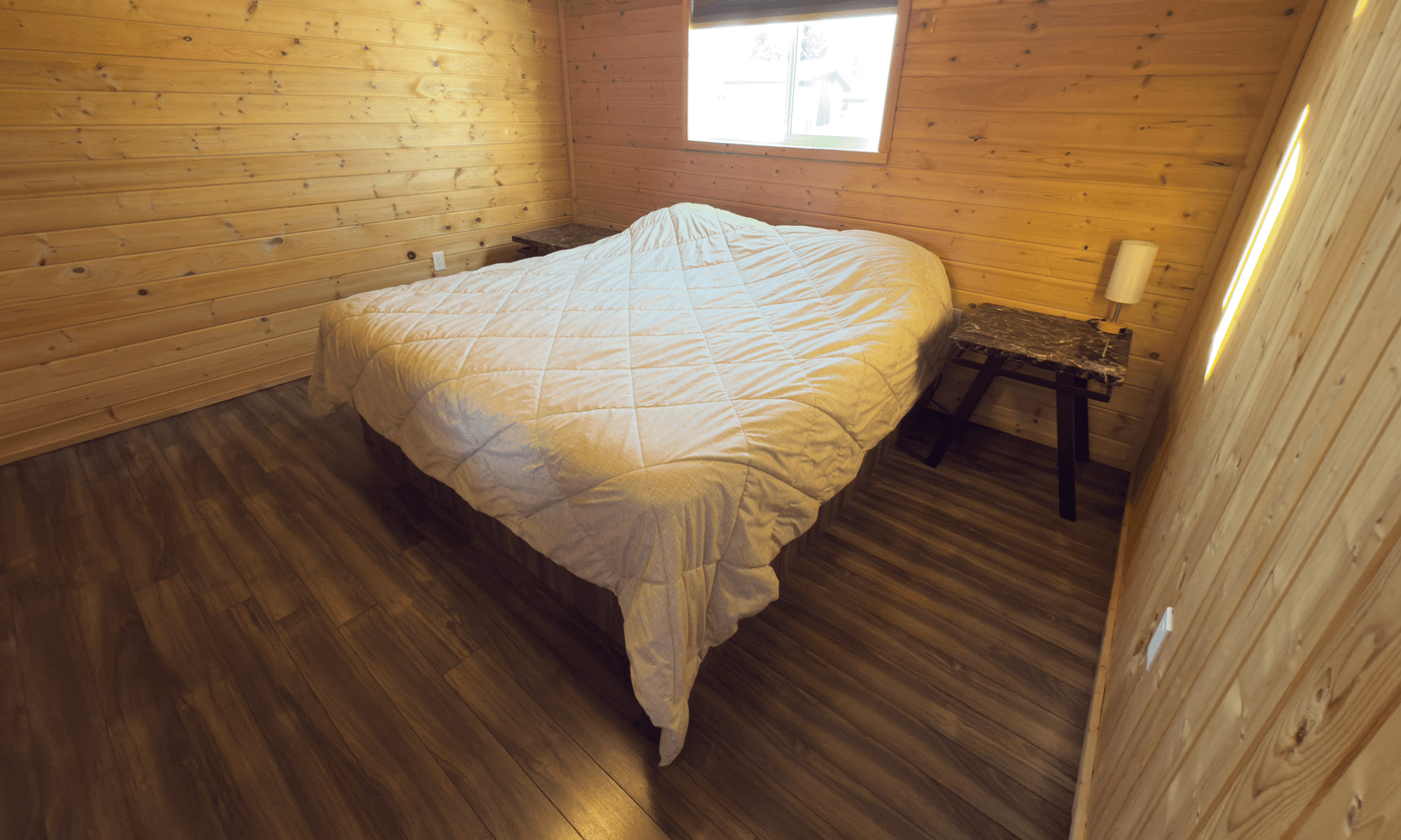 wood-paneled bedroom with a bed, small nightstand, and warm lighting.