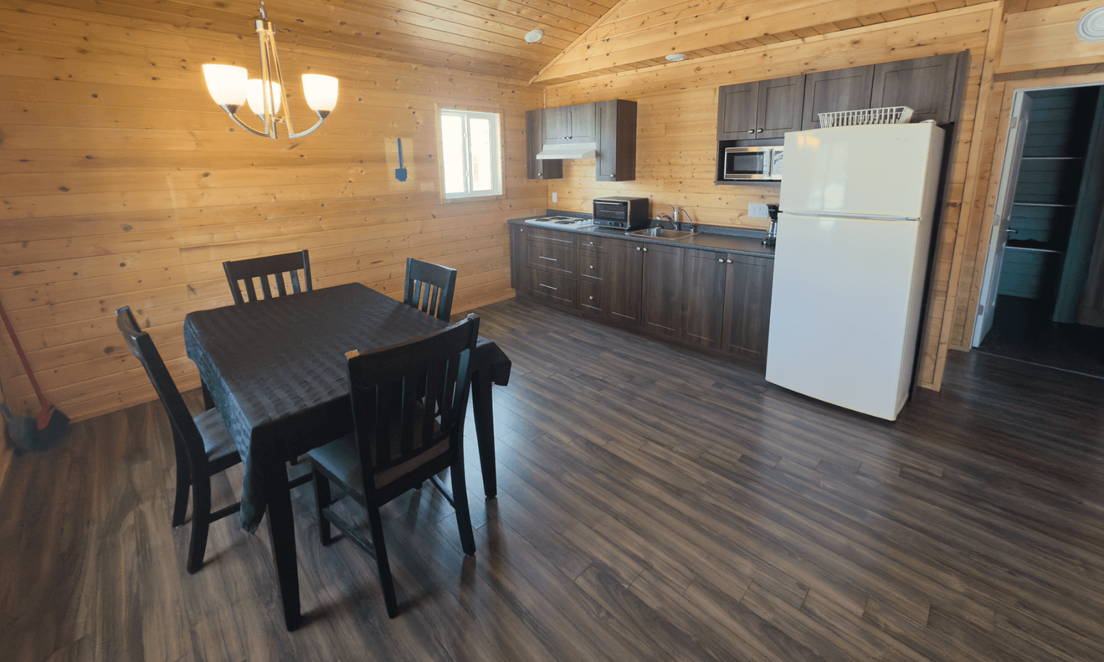 cabin dining area with dark wood table, light paneling, and a chandelier over the table.