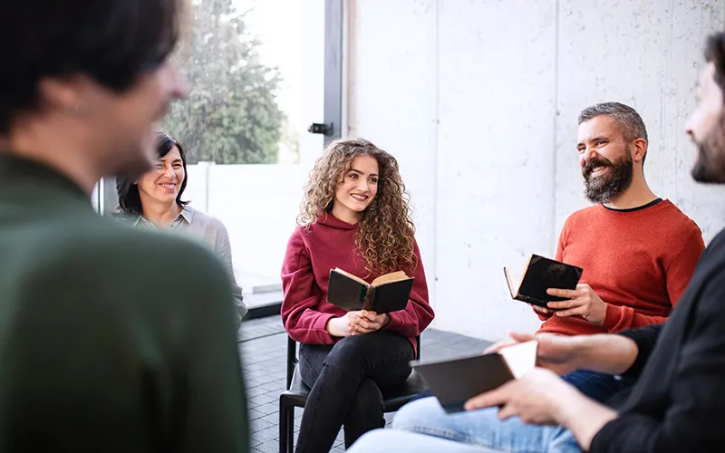 Group of middle-aged to a younger generation sitting on chairs at Grace Chapel discussing the Bible at Dynamic Faith Ministries, Bible study