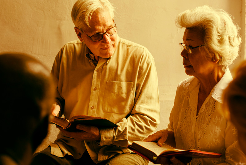 People with their hands folded over their Bibles at Dynamic Faith Ministries