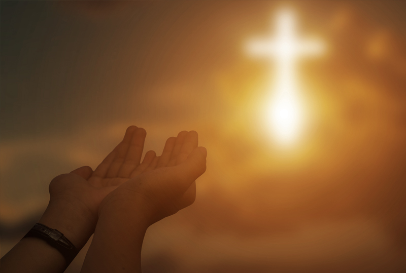 People with their hands folded over their Bibles at Dynamic Faith Ministries