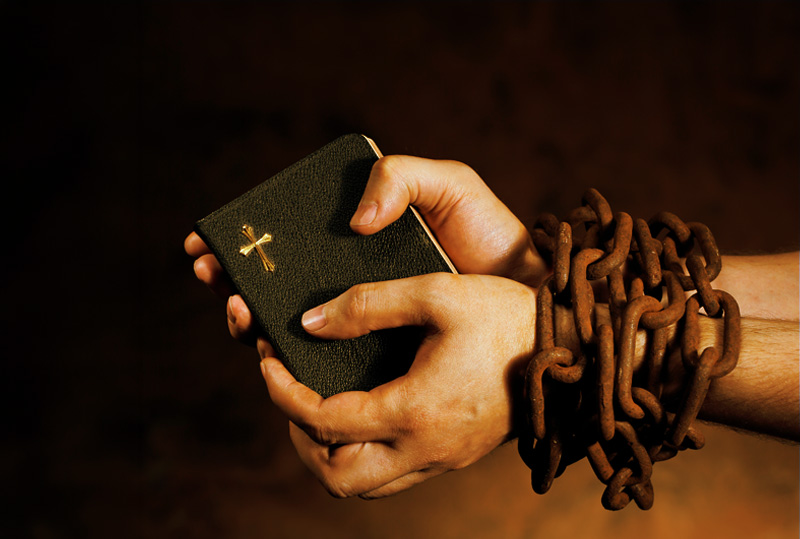 People with their hands folded over their Bibles at Dynamic Faith Ministries