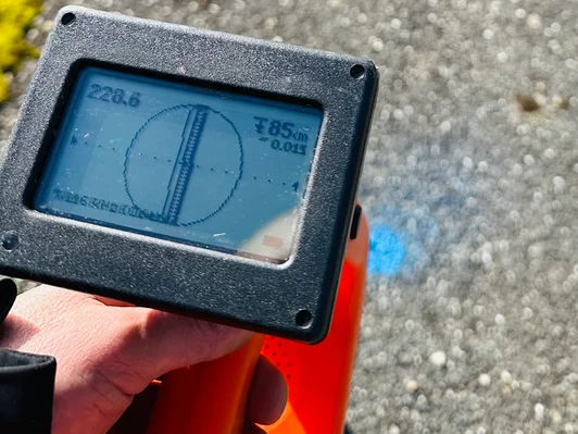 Hand holding a surveying instrument displaying angle measurement on a digital screen.