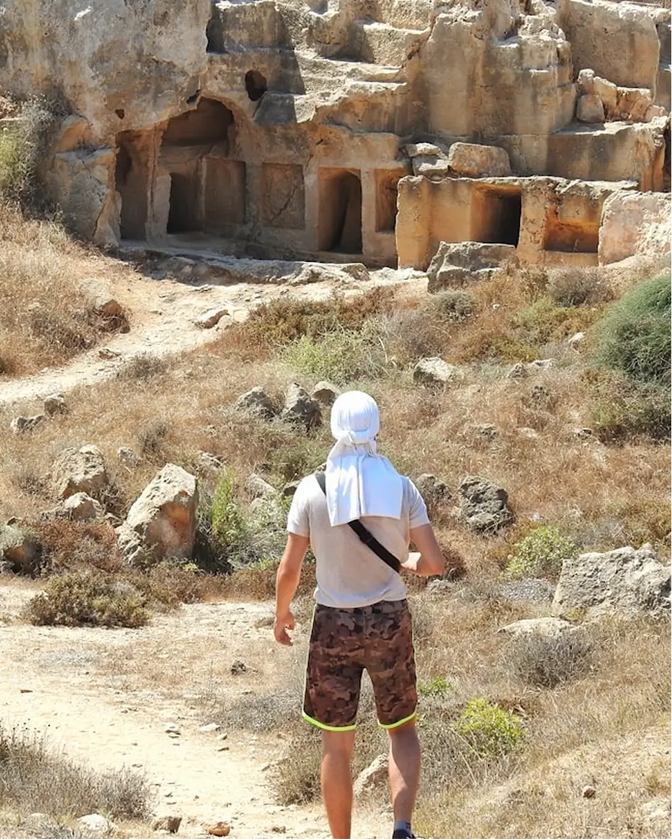Traveller walking toward ancient cave dwellings carved into rocky hills