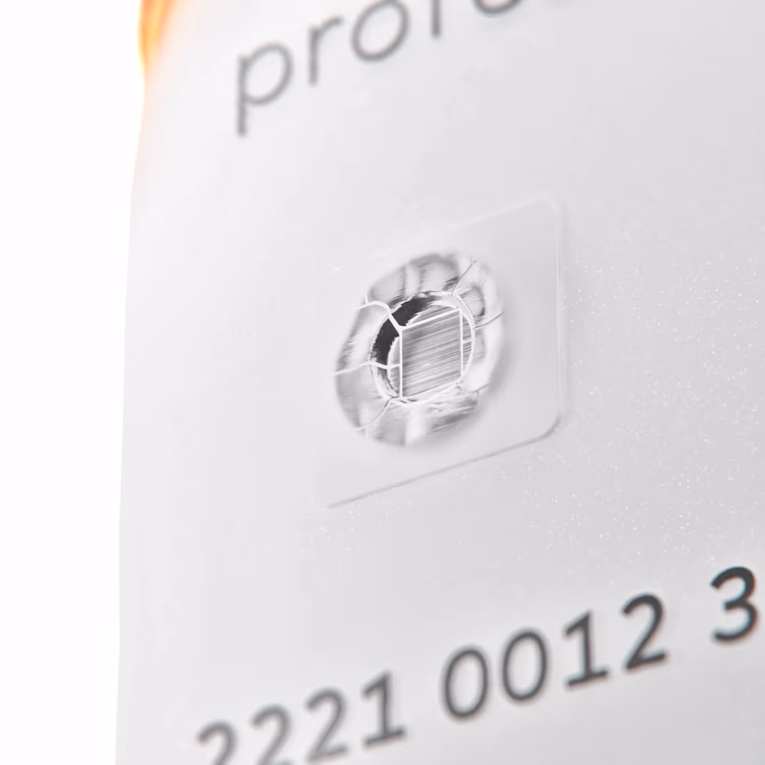 Close-up of a transparent security hologram sticker on a white surface with partial numbers printed nearby.