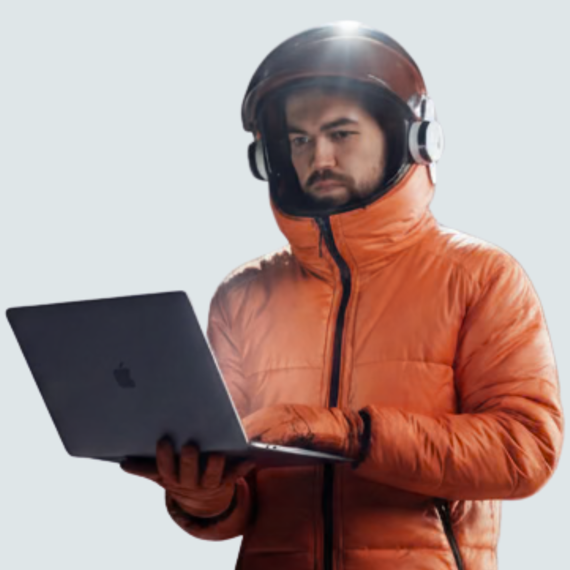 Man in an orange puffer jacket and helmet using a laptop.
