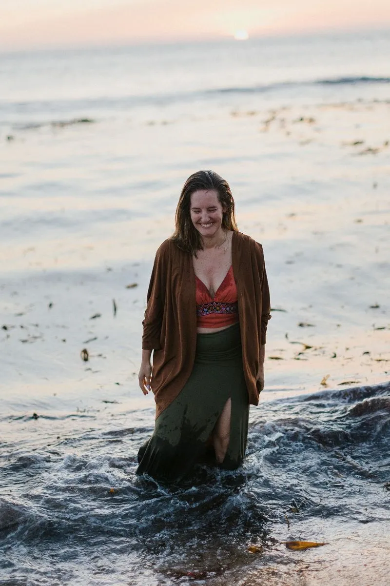 Terapeuta Anica no mar com água pelos joelhos a sorrir genuinamente