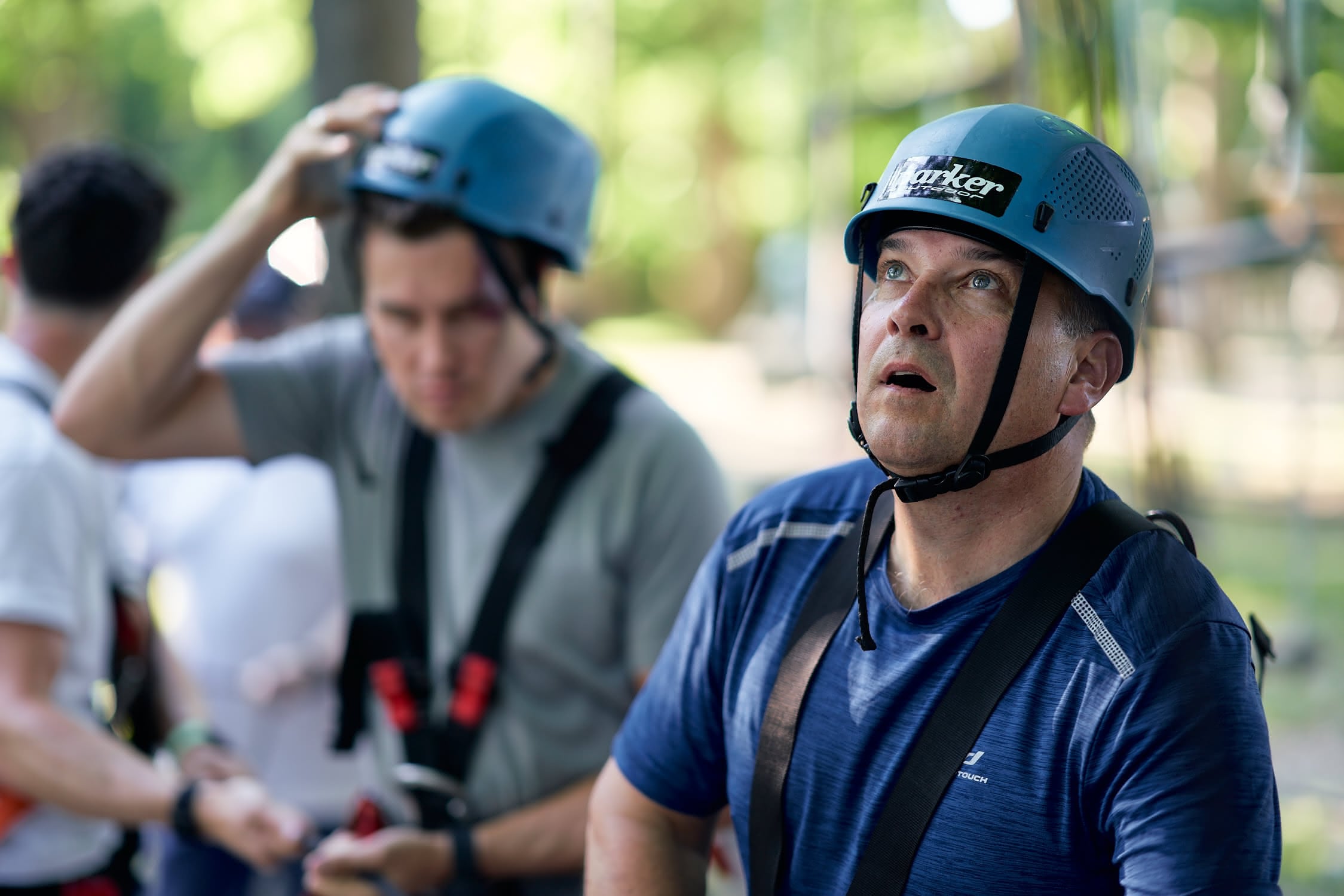 Zwei Männer mit Schutzhelmen und Kletterausrüstung im Freien, der vordere schaut nach oben.