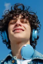 Person using a vacuum cleaner to clean office carpet near desks and chairs.