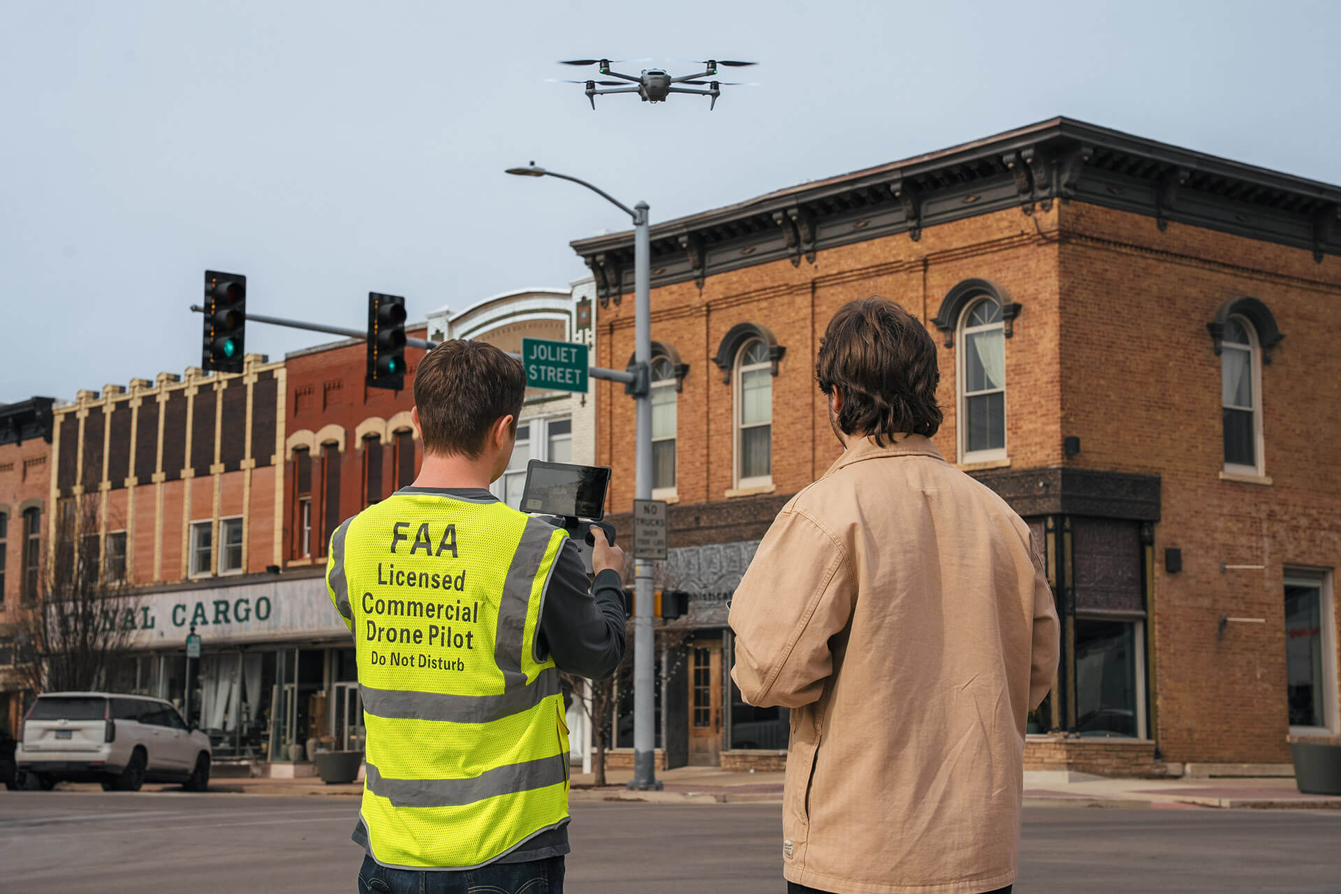 reelCreative crew operating a drone over a street intersection with one wearing a yellow vest labeled FAA Licensed Commercial Drone Pilot.