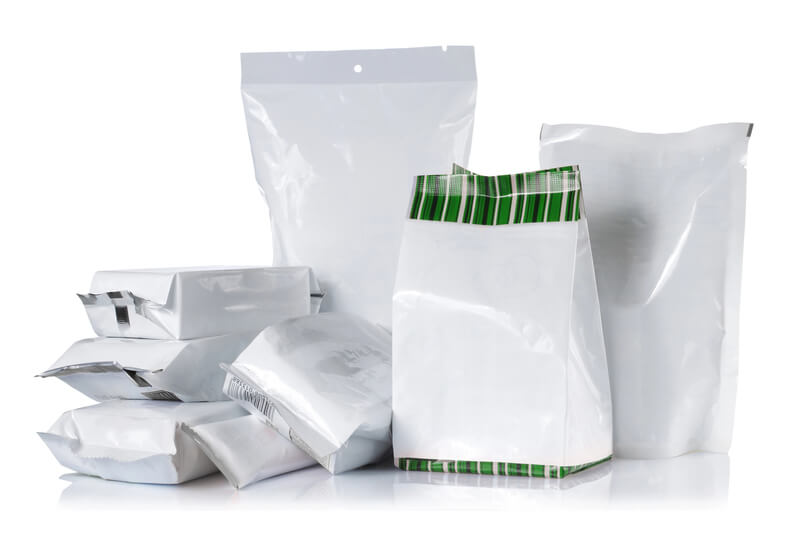 Mehrere verschieden große weiße Lebensmittelverpackungen aus Folie, einige mit grünem Streifenmuster.